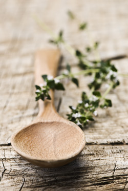 Rustic wooden spoon with fresh herbs on an old wooden board